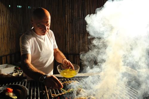 a man cooking food on a grill with smoke at Baia Degli Aranci Suite & Apartments in Vieste