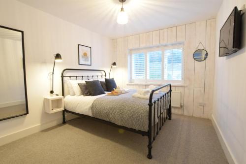 1 dormitorio con cama, ventana y TV en Blackshore House, Wenhaston, en Southwold