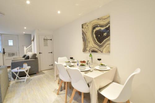 a dining room with a white table and chairs at The Smokehouse Cottage in Southwold