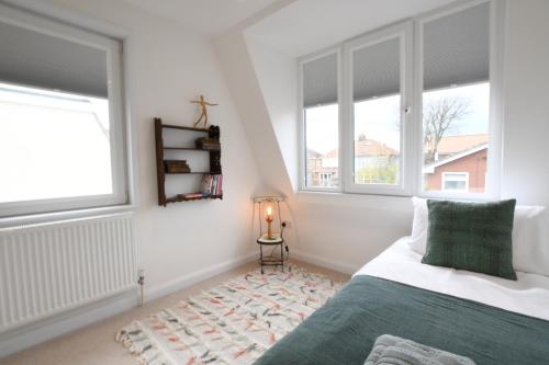 a bedroom with a bed and two windows at Marsh View, Southwold in Southwold