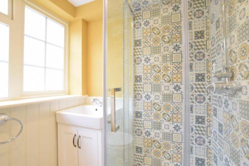 ein Badezimmer mit Waschbecken und Glasdusche in der Unterkunft Parsley Cottage, Southwold in Southwold