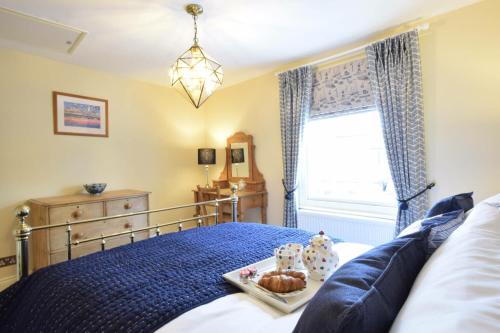 ein Schlafzimmer mit einem Bett, auf dem ein Tablett mit Essen steht in der Unterkunft Parsley Cottage, Southwold in Southwold