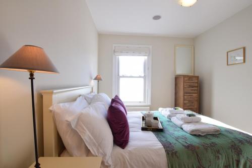 1 dormitorio con 1 cama con toallas y 1 lámpara en Pier View, Southwold en Southwold