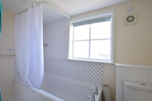 uma casa de banho com uma banheira branca e uma janela em 5 Blackshore, Southwold em Southwold