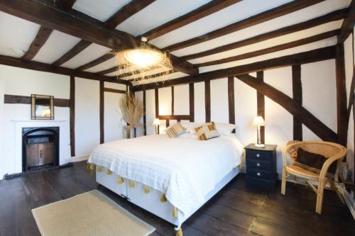 a bedroom with a white bed and a fireplace at Church Farmhouse, Cookley in Halesworth