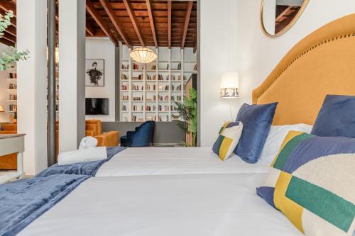 sypialnia z dużym łóżkiem z niebieskimi i żółtymi poduszkami w obiekcie San Lorenzo Collection Homes - Space Maison Apartments w Sewilli