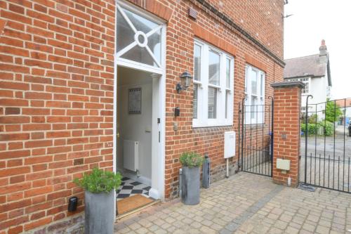 a brick building with a white door and two plants at 1 Eversley Court, Southwold in Southwold