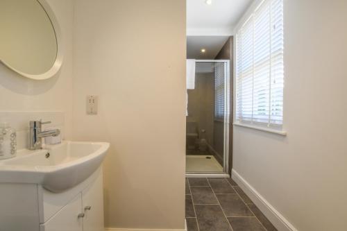 a white bathroom with a sink and a shower at The Gallery, Blythburgh in Blythburgh