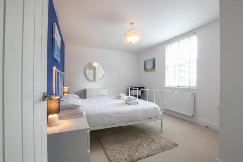 a white bedroom with a bed and a window at The Gallery, Blythburgh in Blythburgh