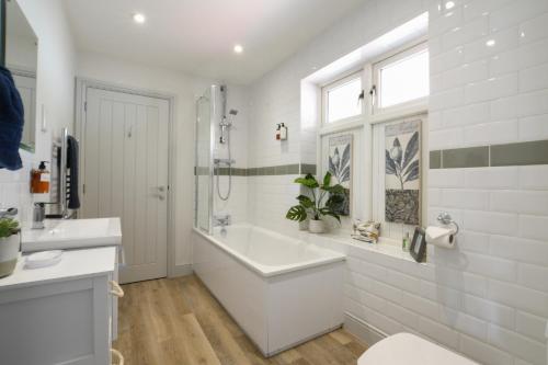 a white bathroom with a tub and a sink at 1 Coconut Cottage, Long Melford in Long Melford