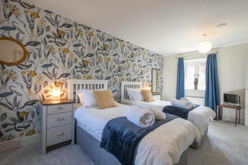 two beds in a bedroom with floral wallpaper at 1 Coconut Cottage, Long Melford in Long Melford