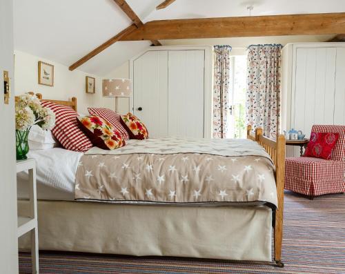 a bedroom with a large bed with red pillows at Stable Cottage at the Grove, Great Glemham in Framlingham