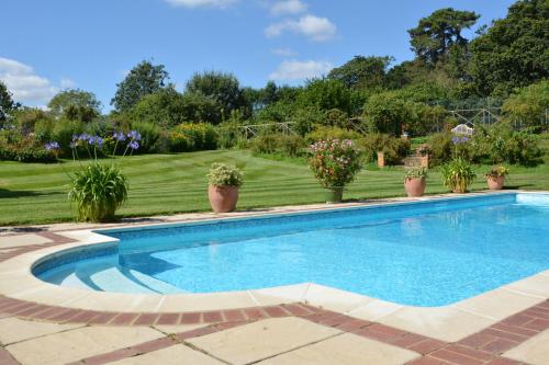 a swimming pool in a yard with potted plants at Stable Cottage at the Grove, Great Glemham in Framlingham