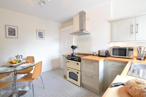 a kitchen with a stove top oven next to a table at Driftwood, Southwold in Southwold