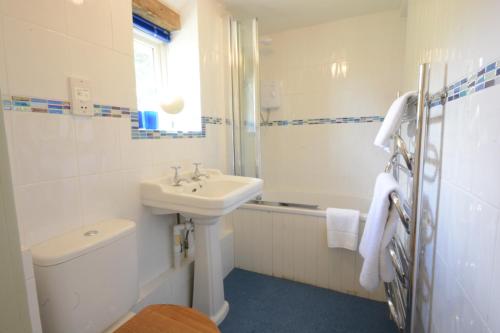 La salle de bains blanche est pourvue d'un lavabo et de toilettes. dans l'établissement Shoemakers Cottage, Friston, à Friston