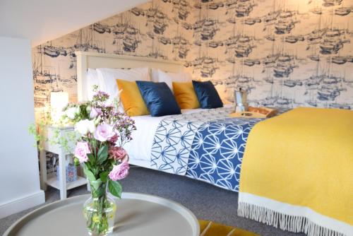 a bedroom with a bed and a vase of flowers on a table at Driftwood, Southwold in Southwold