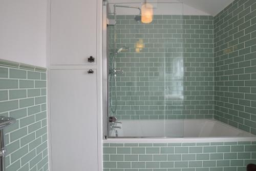 a green tiled bathroom with a tub and a shower at Driftwood, Southwold in Southwold