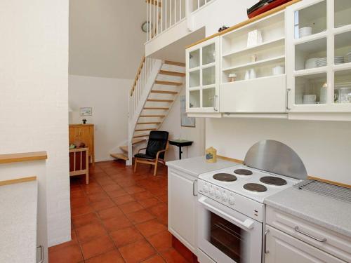 una cucina con piano cottura bianco e scala di 4 person holiday home in Bl vand a Blåvand