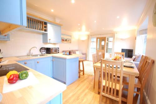 a kitchen with blue cabinets and a table with vegetables on it at Garden Cottage, Southwold in Southwold