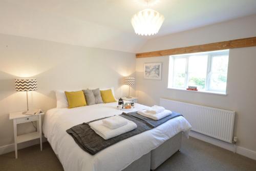 a bedroom with a large bed with two towels on it at Fig Cottage, Pettistree in Woodbridge