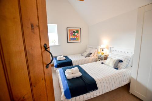 two beds in a room with towels on them at Three Chantry Barns, Orford in Orford