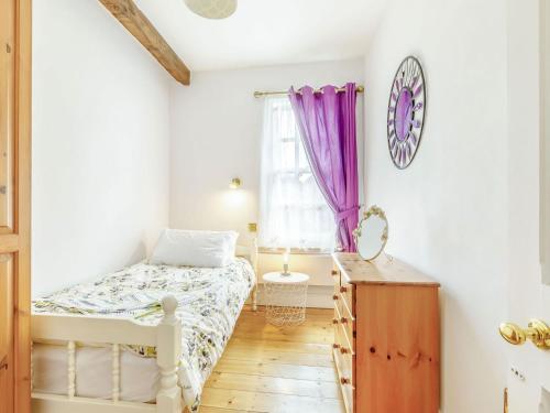 a bedroom with a bed and a window with purple curtains at Nightingale House in Ottery Saint Mary