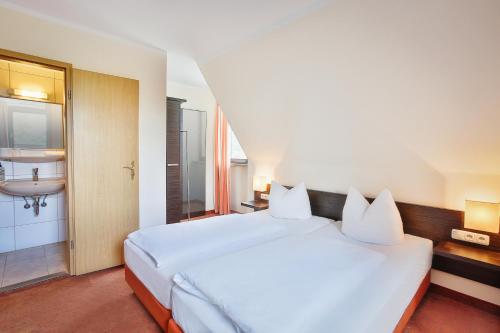 a bedroom with a large white bed and a sink at Berggasthof Banzer Wald in Bad Staffelstein
