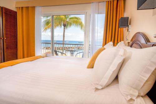 a bedroom with a bed with a view of the ocean at Hotel Bakoua Martinique in Les Trois-Îlets