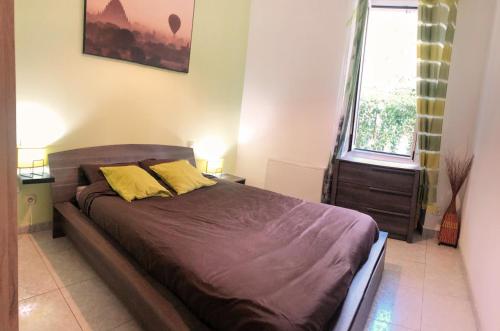 uma cama com duas almofadas amarelas num quarto em T2 entièrement équipé et refait à neuf à 10mn Alès em La GrandʼCombe