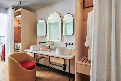 La salle de bains est pourvue de 2 lavabos, d'une chaise et de miroirs. dans l'établissement Virgin Hotels New York City, à New York