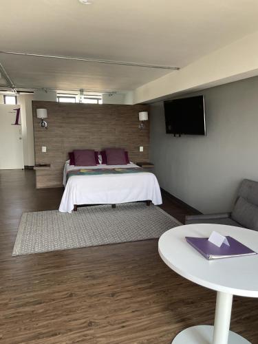 a bedroom with a bed and a table and a tv at Vintage Lofts in Guadalajara