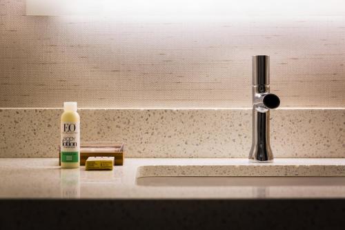 a bathroom sink with a bottle of soap and a faucet at EVEN Hotel Omaha Downtown - Old Market by IHG in Omaha