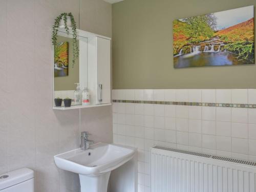 ein weißes Badezimmer mit einem Waschbecken und einem Spiegel in der Unterkunft Outhwaite Cottage in Scalehouses