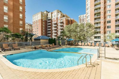 a large swimming pool with chairs and buildings at Sensational 1 Bedroom Condo At Ballston place With Gym in Arlington