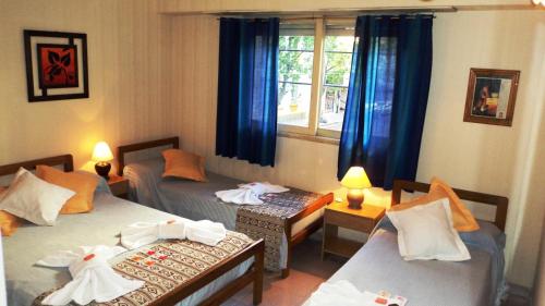 Habitación con 2 camas y ventana con cortinas azules. en Hotel Cielo Azul en Mar del Plata