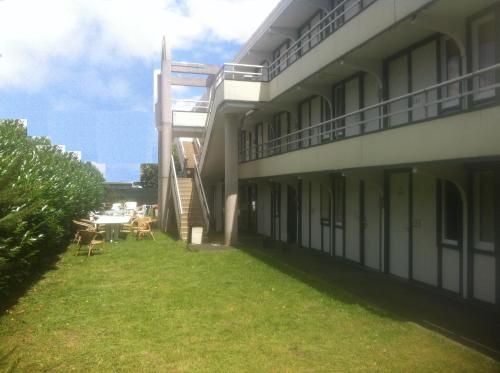an external view of a building with a grass yard at Nouvelle Classe Hotel in Châtellerault