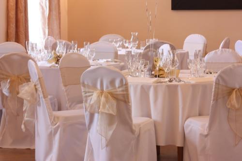 a dining room with white tables and chairs with bows at Annandale Arms Hotel in Moffat