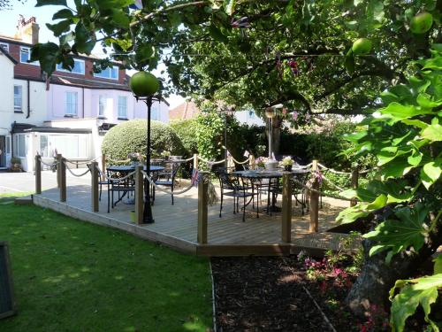 a wooden deck with tables and chairs in a yard at Sonachan House in Paignton