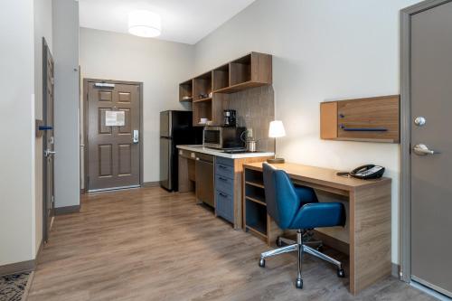 a small kitchen with a desk and a blue chair at Candlewood Suites Grand Junction by IHG in Grand Junction