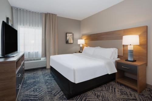 a hotel room with a bed and a flat screen tv at Candlewood Suites Grand Junction by IHG in Grand Junction