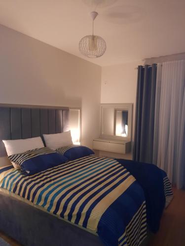 Schlafzimmer mit einem Bett mit blauen und weißen Streifen in der Unterkunft Mia Apartments in Podgorica