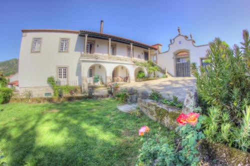 una gran casa blanca con un patio con flores en Quinta de São Roque en Vila Nova de Cerveira