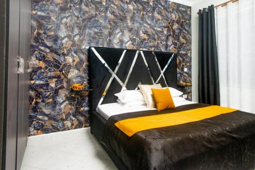 a bedroom with a bed with a black and yellow blanket at Boujee Residence Apartment in Kampala
