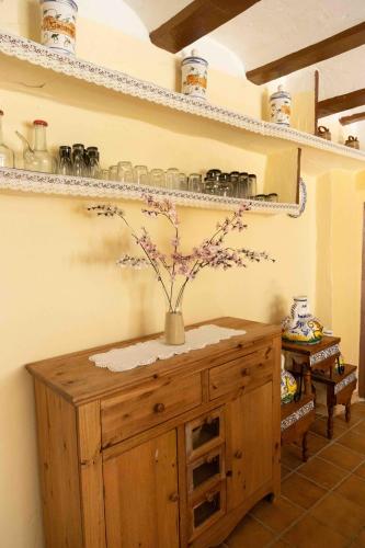 a wooden cabinet with a vase with flowers on it at MAS DE BONDIA - Casa Herrero in Alpuente
