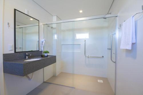 a bathroom with a glass shower and a sink at Hotel Darolt Criciúma in Criciúma