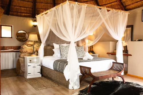a bedroom with a bed with a canopy at Rain Farm Game Lodge in uMhlali
