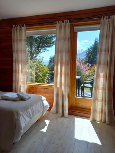 a bedroom with a bed and a large window at Casa del Lago Villa La Angostura in Villa La Angostura