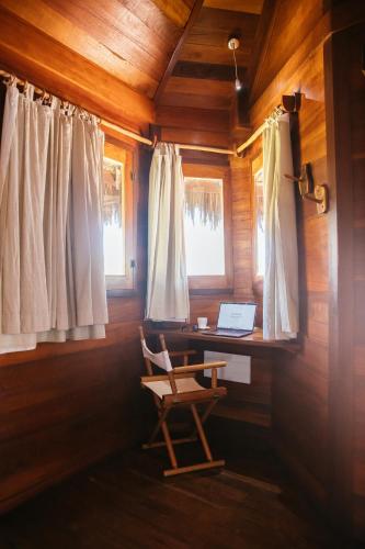 a chair in a room with a desk and windows at Hurricane Jeri in Jericoacoara
