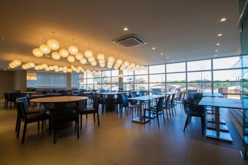 a restaurant with tables and chairs and large windows at Hotel Darolt Criciúma in Criciúma