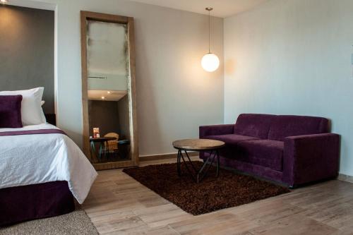 a bedroom with a bed and a purple couch and a table at NEhotel Nueva Estancia in León